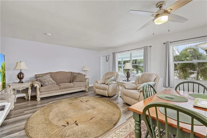 Living room with a textured ceiling, hardwood / wood-style floors, and ceiling fan