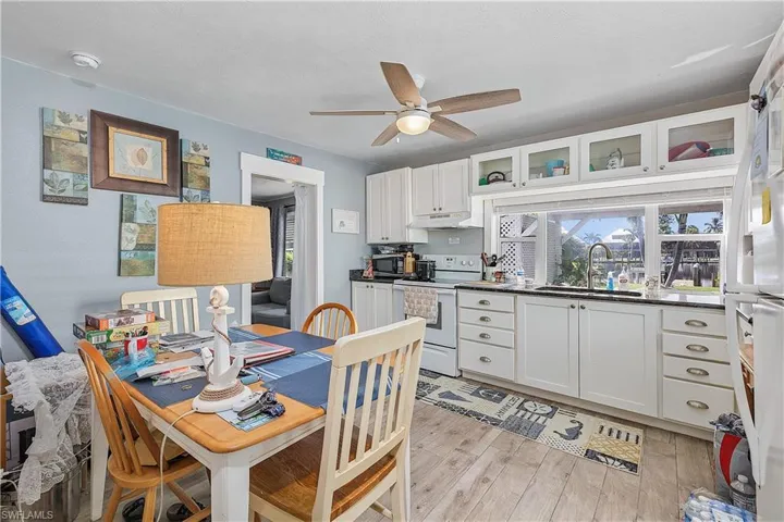 Kitchen featuring white cabinets, white appliances, ceiling fan, light hardwood / wood-style flooring, and sink