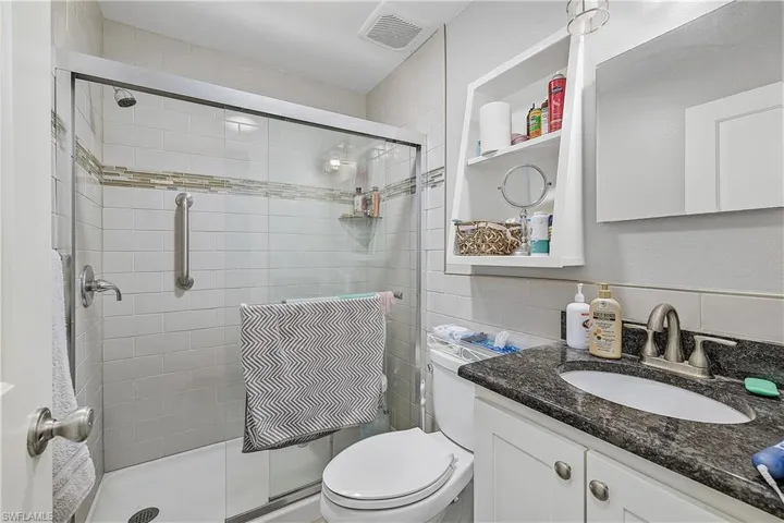 Bathroom featuring walk in shower, vanity, and toilet