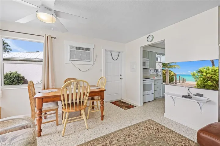 Dining room with an AC wall unit, ceiling fan, sink, and a textured ceiling