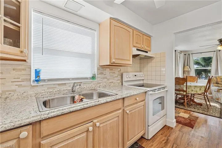 Kitchen with ceiling fan, sink, light brown cabinetry, white range with electric cooktop, and light wood-type flooring