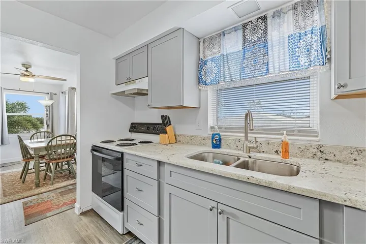 Kitchen with gray cabinets, sink, light hardwood / wood-style flooring, white range with electric stovetop, and ceiling fan