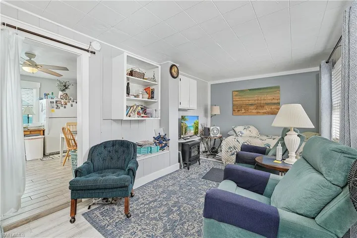 Living room with built in shelves, ceiling fan, and hardwood / wood-style floors