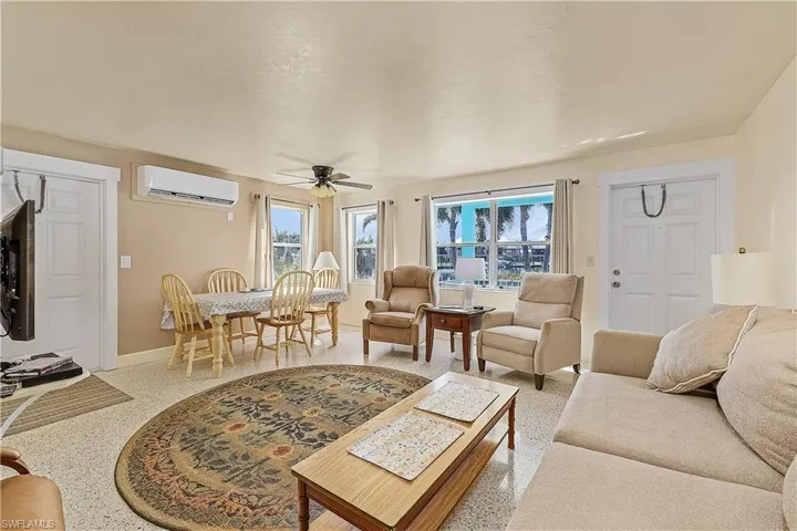 Living room featuring a wealth of natural light, a wall unit AC, and ceiling fan