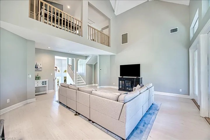 Living room with a towering ceiling and light hardwood / wood-style floors