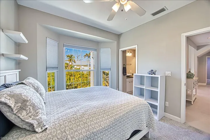 Carpeted bedroom featuring ceiling fan and ensuite bath