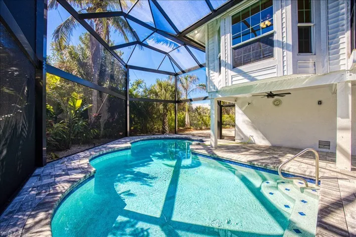 View of pool with a patio, ceiling fan, and glass enclosure