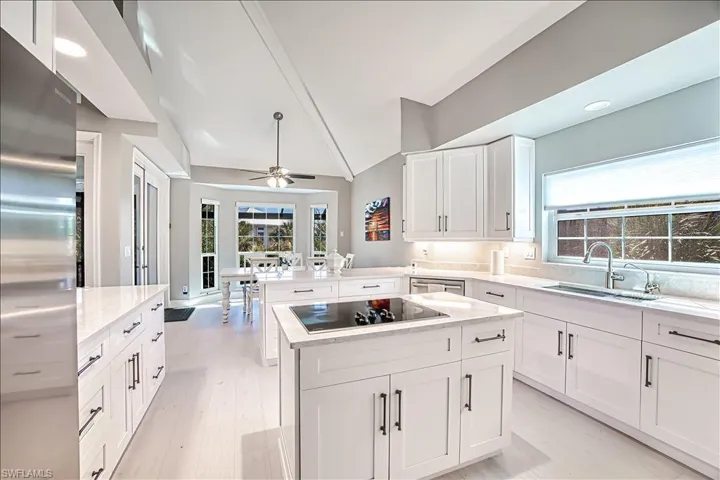 Kitchen with sink, black electric cooktop, stainless steel fridge, kitchen peninsula, and a kitchen island