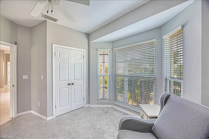 Living area featuring light carpet and ceiling fan
