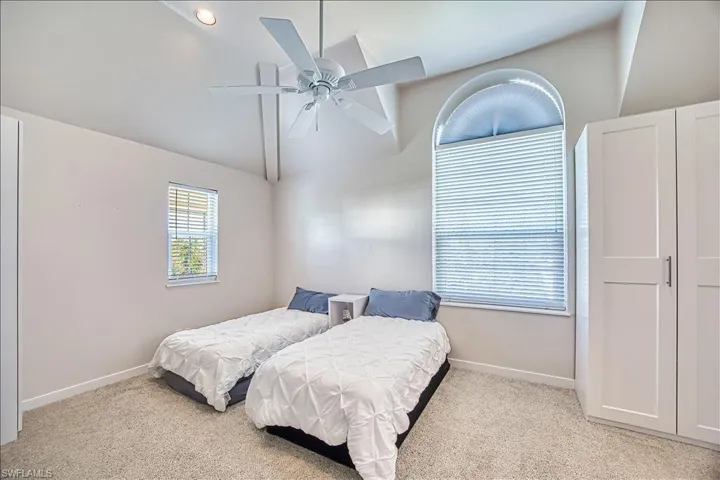 Bedroom featuring lofted ceiling, light carpet, and ceiling fan