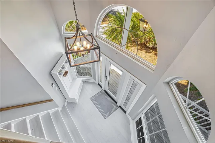 Entrance foyer with an inviting chandelier, a towering ceiling, plenty of natural light, and light hardwood / wood-style floors