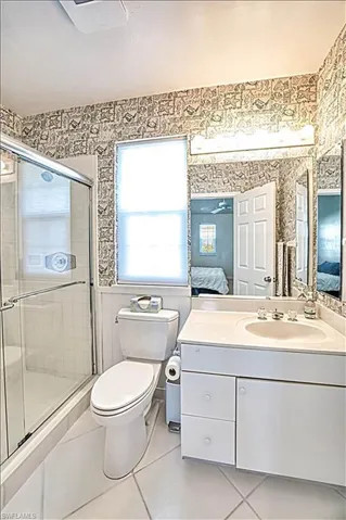 Bathroom featuring vanity, walk in shower, tile patterned floors, and toilet