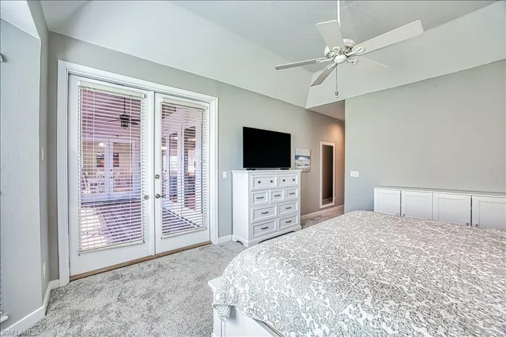 Carpeted bedroom with access to outside, french doors, ceiling fan, and vaulted ceiling