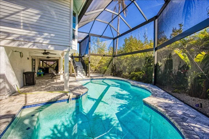 View of pool featuring ceiling fan, a patio, and glass enclosure
