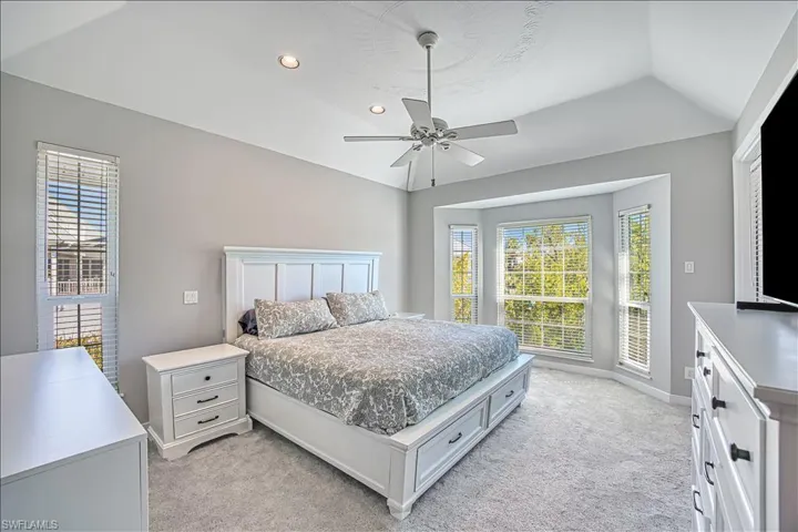 Carpeted bedroom with lofted ceiling and ceiling fan