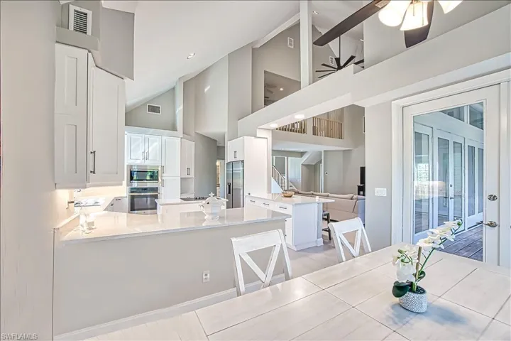 Kitchen with a breakfast bar area, high vaulted ceiling, appliances with stainless steel finishes, kitchen peninsula, and white cabinets