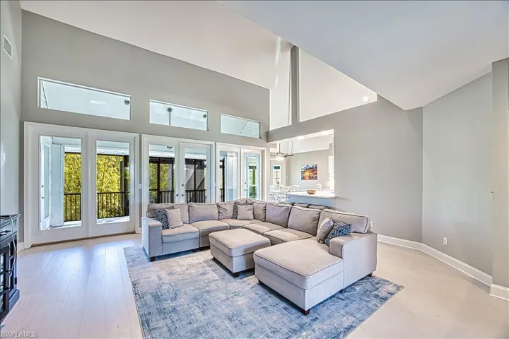 Living room featuring french doors, a high ceiling, and light wood-type flooring
