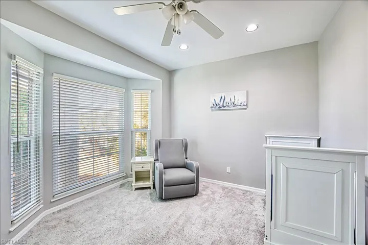 Living area with light carpet, ceiling fan, and a healthy amount of sunlight