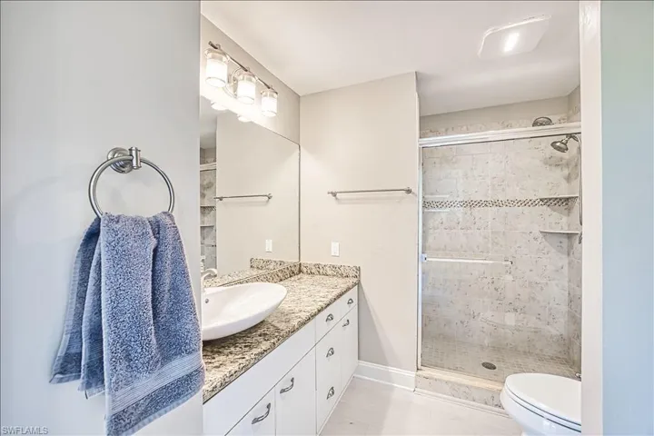Bathroom featuring vanity, an enclosed shower, and toilet