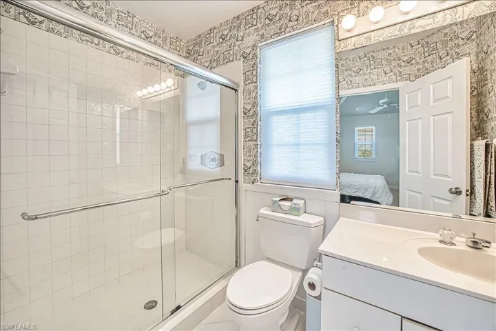 Bathroom featuring walk in shower, vanity, and toilet