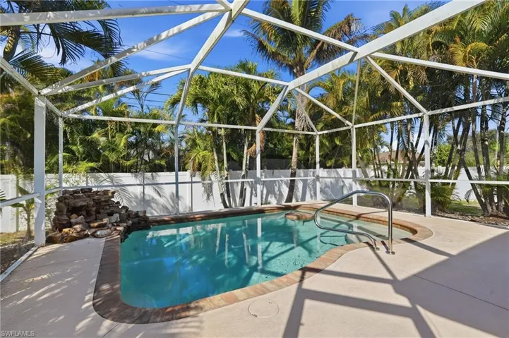 Pool featuring a built-in table for relaxed in-water lounging, paired with a natural rock waterfall that adds soothing sound, movement, and a touch of tropical elegance.