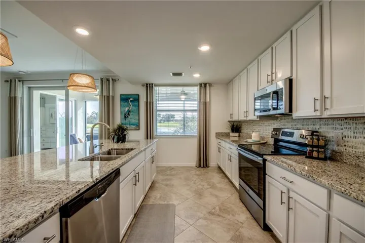 Kitchen featuring hanging light fixtures, sink, white cabinets, appliances with stainless steel finishes, and tasteful backsplash
