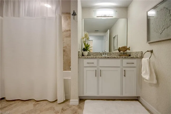 Bathroom featuring vanity and shower / bath combination with curtain