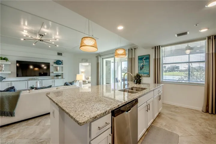 Kitchen with white cabinetry, a kitchen island with sink, dishwasher, pendant lighting, and sink