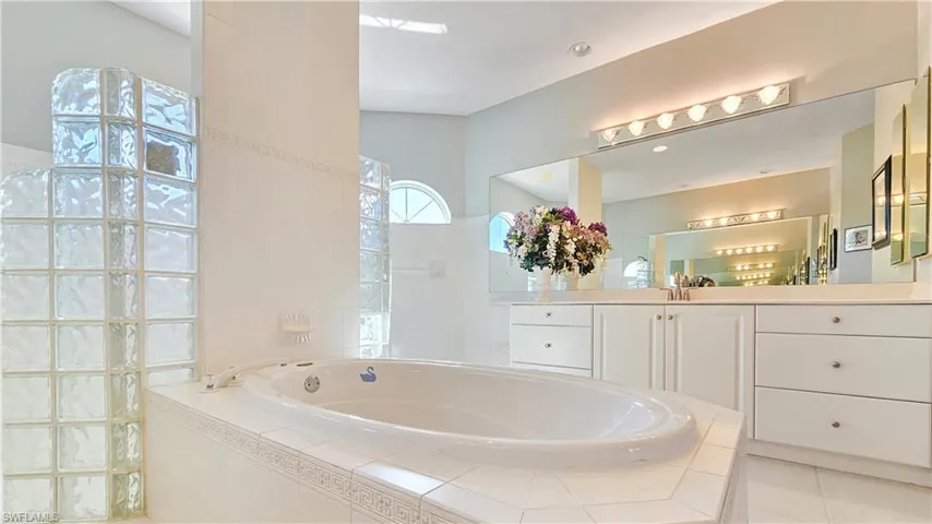 Bathroom featuring vanity, tiled bath, and tile patterned floors