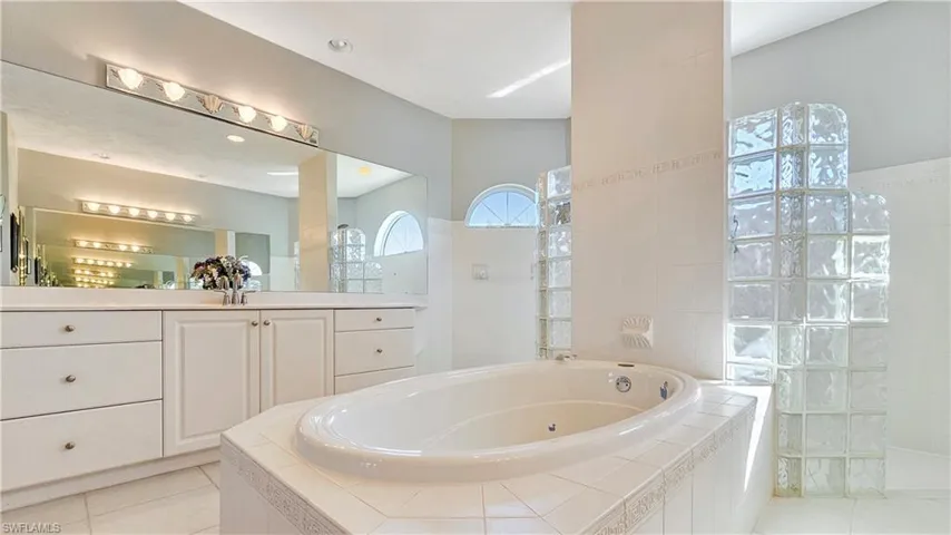 Bathroom with a relaxing tiled tub, tile patterned floors, and vanity
