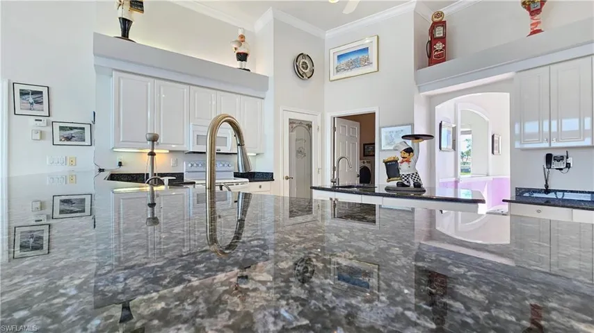 Kitchen with sink, crown molding, dark stone countertops, white appliances, and white cabinets