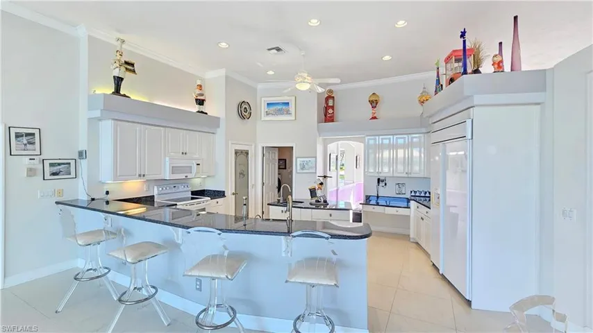 Kitchen featuring crown molding, white appliances, a breakfast bar area, white cabinets, and kitchen peninsula