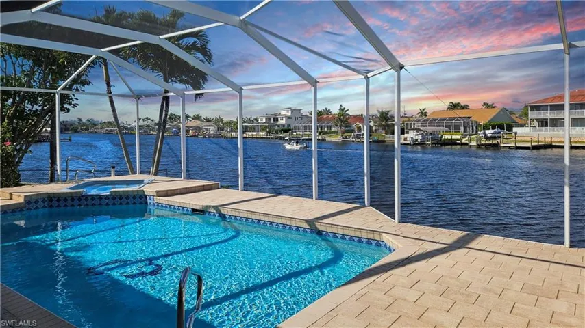 Pool at dusk with a patio, an in ground hot tub, a water view, and glass enclosure