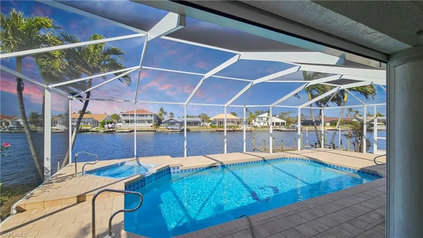 Pool at dusk with a water view, a lanai, a patio area, and a boat dock