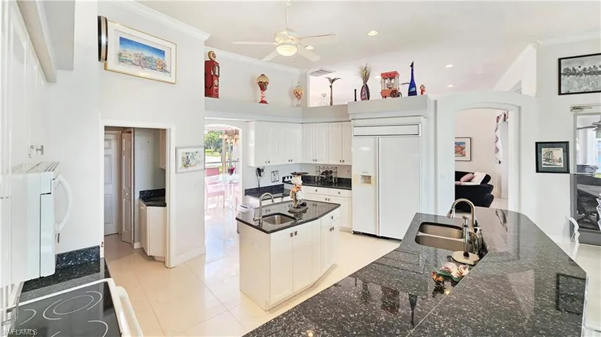 Kitchen featuring white cabinetry, paneled built in refrigerator, a center island, and sink