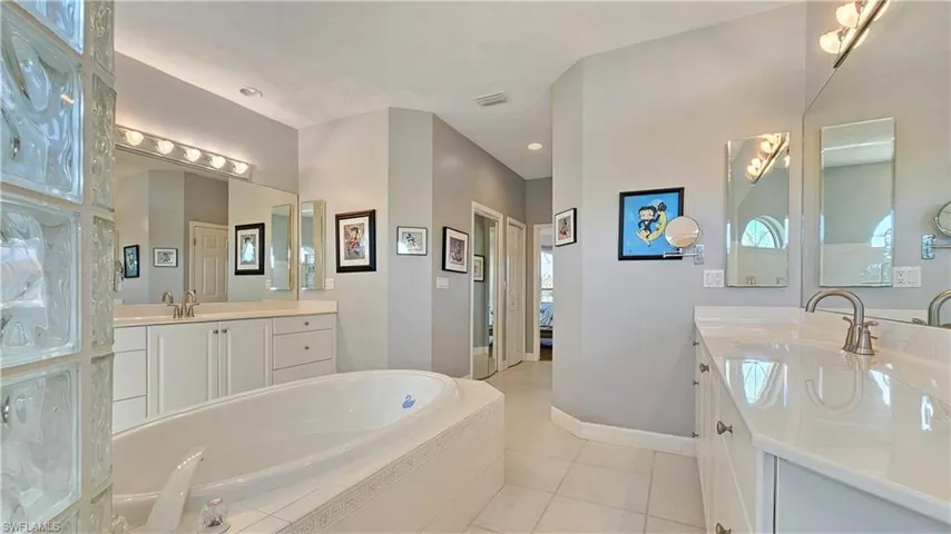 Bathroom featuring vanity, tiled tub, and tile patterned floors