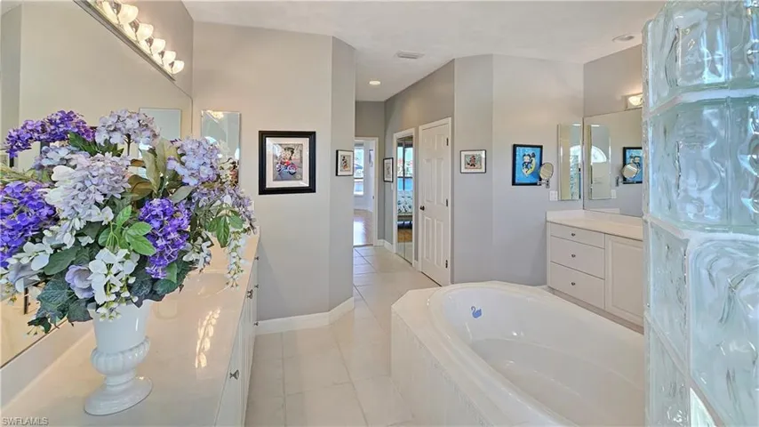 Bathroom featuring vanity, tile patterned flooring, and a relaxing tiled tub