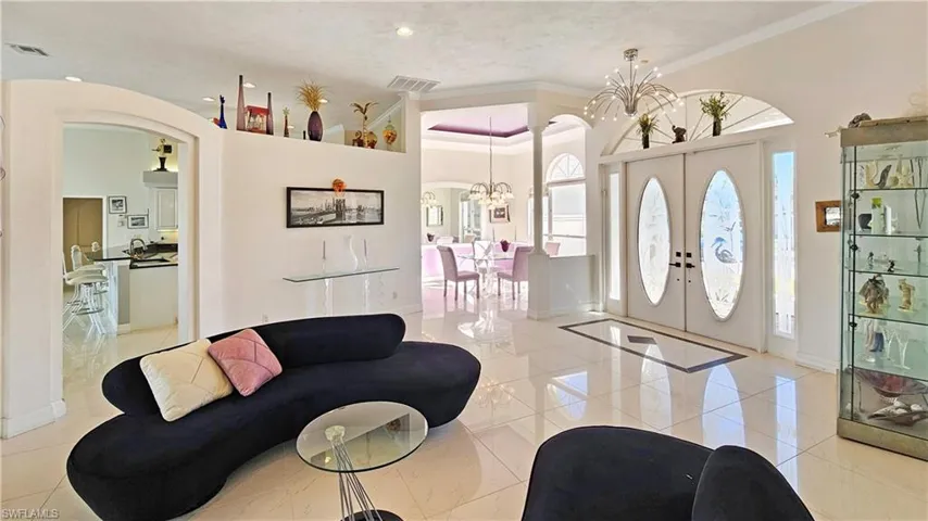 Foyer featuring french doors, ornamental molding, a chandelier, and light tile patterned floors