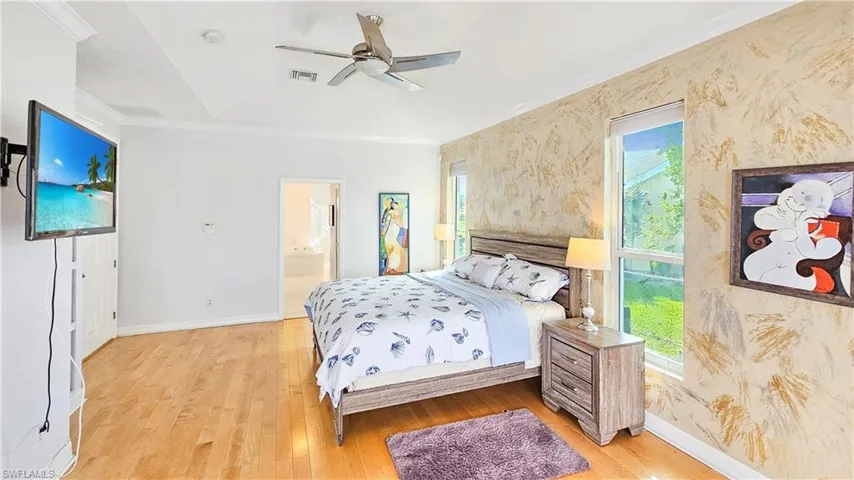 Bedroom with ceiling fan, ornamental molding, connected bathroom, and light hardwood / wood-style floors