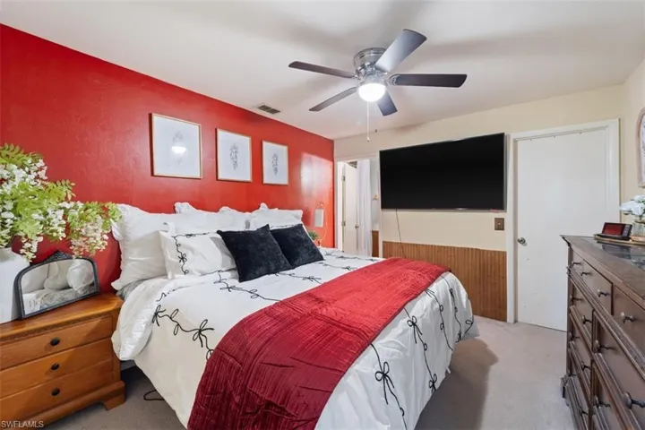 Bedroom with light carpet, a ceiling fan, and a closet