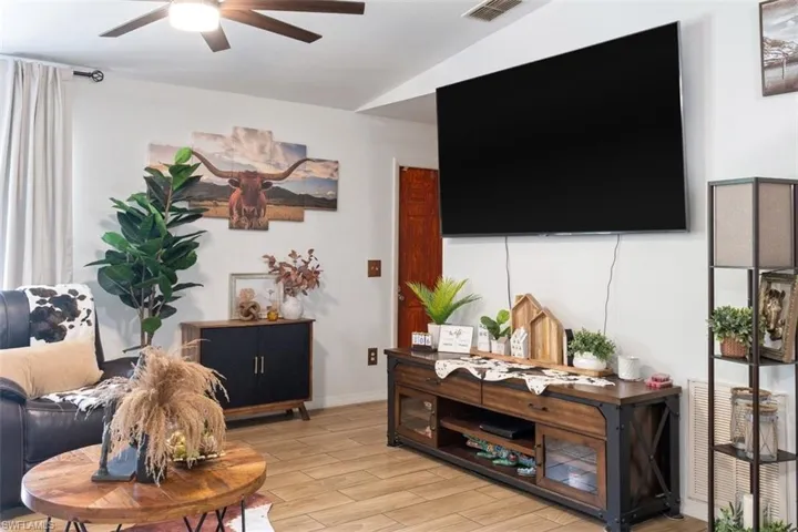 Living room with a ceiling fan, wood tiled floors, and vaulted ceiling