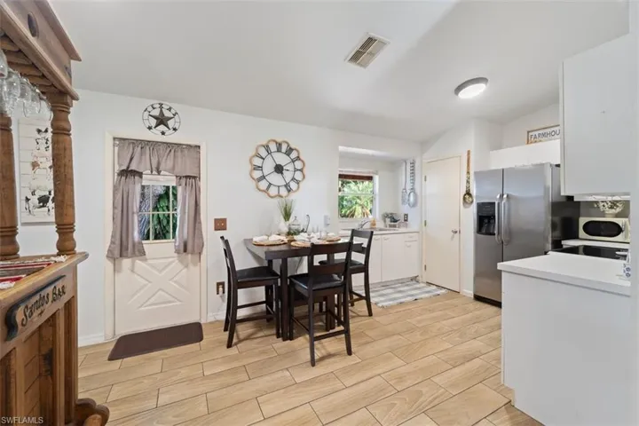Kitchen with wood finish floors, light countertops, white cabinetry, and stainless steel fridge with ice dispenser