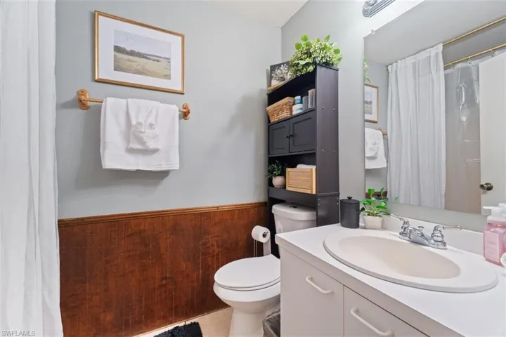 Full bathroom with a shower with shower curtain, vanity, and a wainscoted wall
