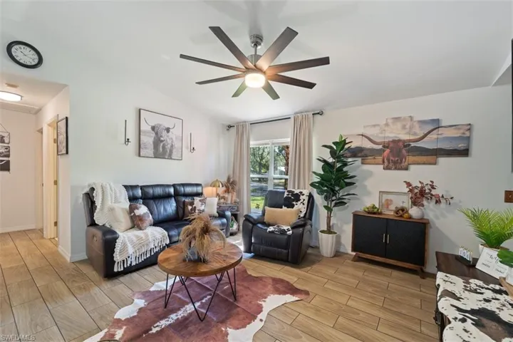 Living room featuring wood finish floors, ceiling fan, and lofted ceiling