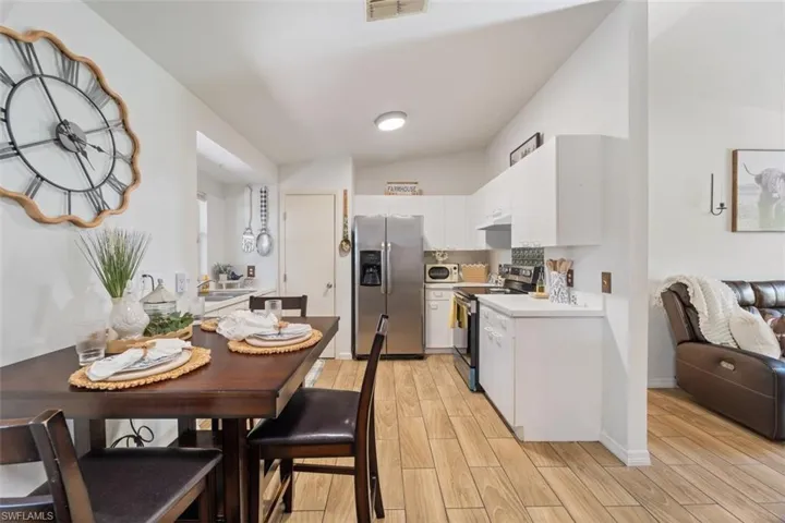 Kitchen featuring light countertops, wood finish floors, stainless steel appliances, white cabinets, and lofted ceiling