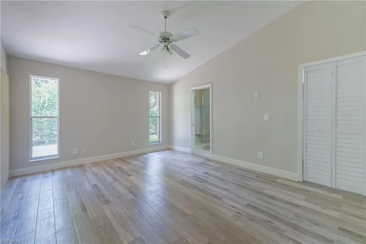 Empty room with plenty of natural light, light wood-style flooring, a ceiling fan, and high vaulted ceiling