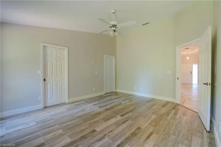 Spare room with light wood-type flooring, ceiling fan, and baseboards