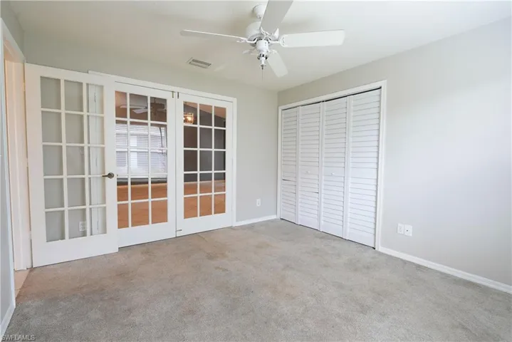 Unfurnished bedroom with carpet floors, a closet, ceiling fan, baseboards, and french doors