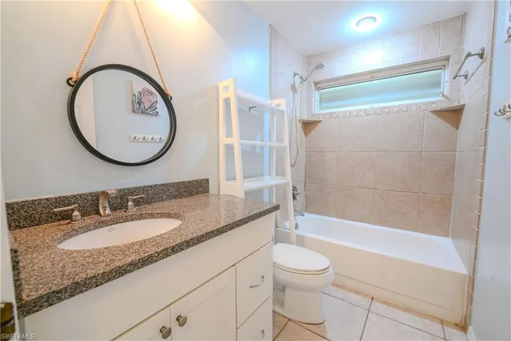 Bathroom with vanity, bathing tub / shower combination, toilet, and tile patterned floors