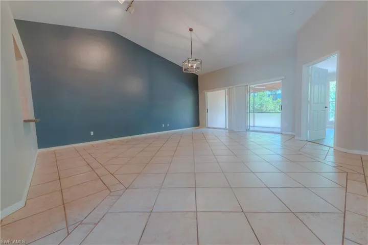 Unfurnished room with light tile patterned floors, vaulted ceiling, and baseboards